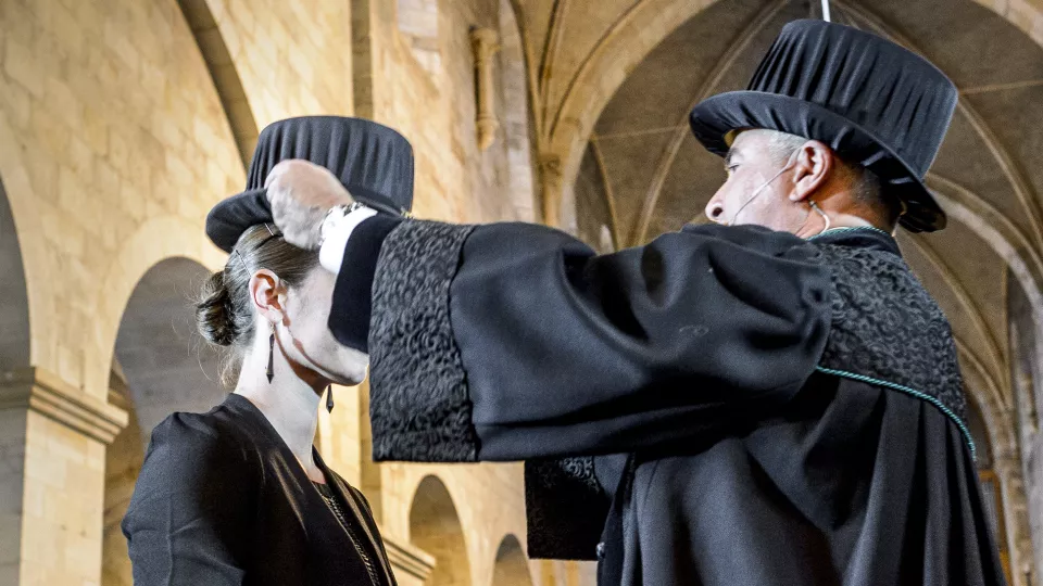 Two people with black robes and black hats. Photo.