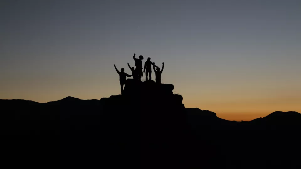 Silhouette of a group of people who have climbed a mountain. Photo.
