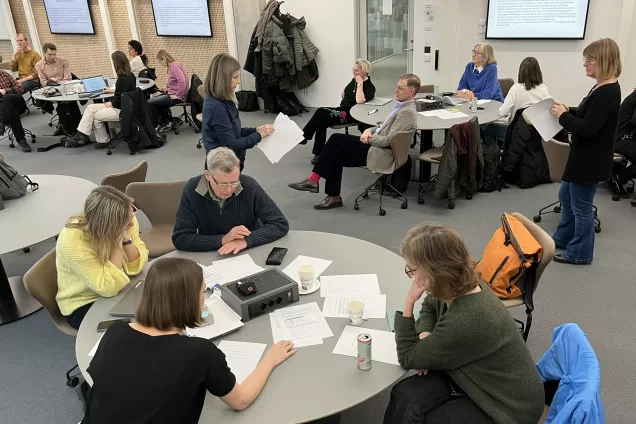 People talking at round tables in a learning classroom. Photo.