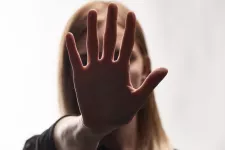 A woman holds her hand in front of her face