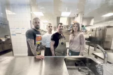 4 persons in a kitchen. Photo.