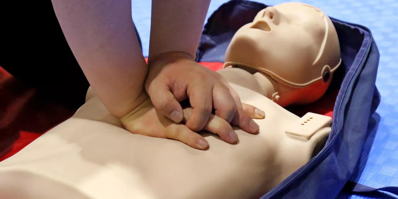 Två händer som gör hjärt-lung-räddning på en docka.