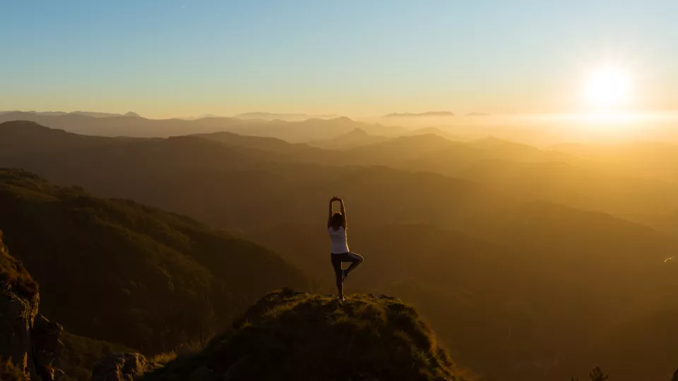 Yogi på en bergstopp i solnedgången. Foto.