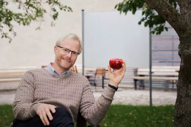 Man med rött äpple. Foto.