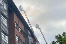 Två brandstegar i rök upphissade längs fasaden på BMC. Foto.